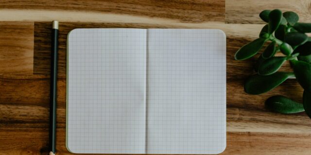 Bolígrafo y cuaderno sobre una mesa de madera para escribir una nota